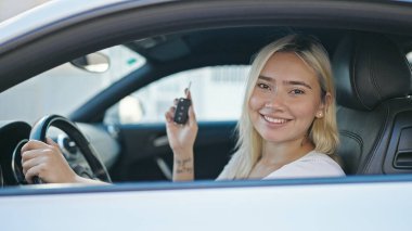 Genç, güzel, İspanyol bir kadın gülümsüyor. Elinde yeni arabanın anahtarı var.