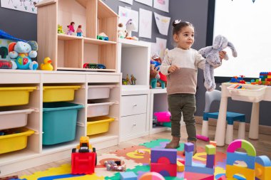 Anaokulunda kendine güvenen sevimli İspanyol kız gülümsüyor.