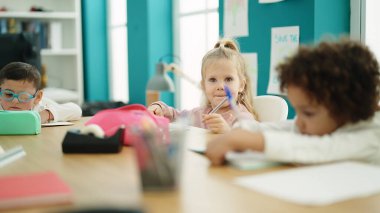 Sınıfta masada oturmuş ders çalışan bir grup çocuk.