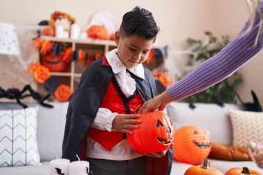 Kostümlü sevimli İspanyol çocuk evde balkabağı sepetinde şeker alıyor.