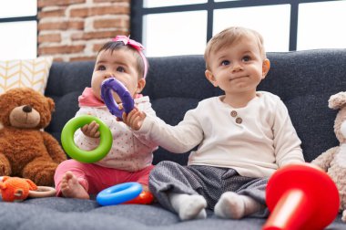 Sevimli kız ve oğlan evdeki kanepede oturup basketbol oynuyorlar.