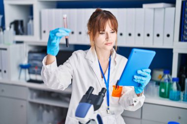 Laboratuvarda kan analizi ve dokunmatik doku tutan genç kadın bilim adamı.