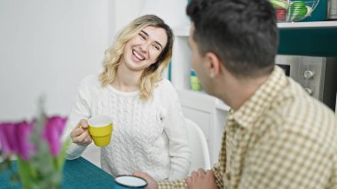 Kadın ve erkek, yemek odasında kahve içerek masada oturuyorlar.