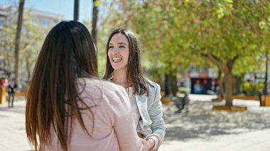 Parkta bir arada duran kendine güvenen iki kadın.