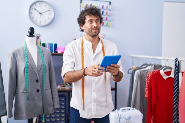 Genç İspanyol terzi. Giysi fabrikasında dokunmatik ped kullanarak gülümsüyor.