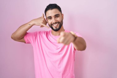 İspanyol genç adam pembe arka planda durup gülümsüyor telefonda konuşuyor ve seni işaret ediyor. Ara beni.. 