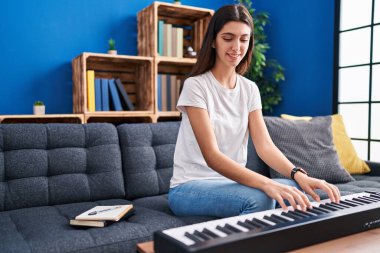 Genç, güzel İspanyol kadın parkta kanepede piyano çalıyor.