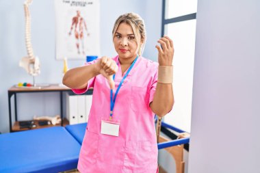 Ağrı kesici kliniğinde çalışan genç İspanyol kadın bileklik takıyor ve kızgın bir yüz ifadesi takıyor. 