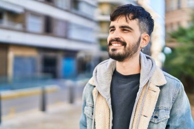 Young hispanic man smiling confident looking to the side at street