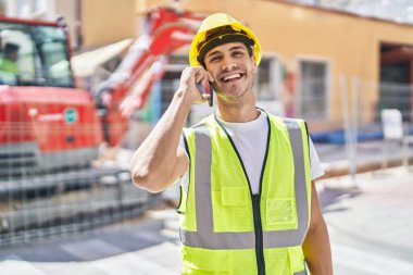 Genç İspanyol mimar gülümsüyor. Parkta akıllı telefondan konuşuyor.