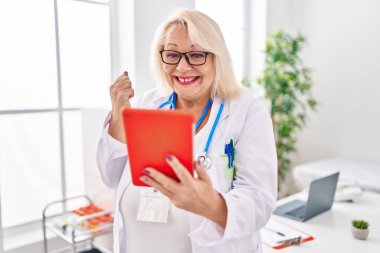 Orta yaşlı, beyaz bir kadın online randevu için çalışıyor. Gururla bağırıyor, zaferi kutluyor ve kollarını kaldırdığı için çok heyecanlı. 