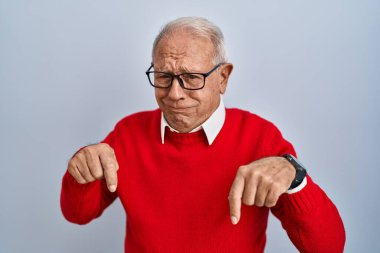 İzole edilmiş arka planda duran yaşlı adam üzgün ve üzgün görünüyor, parmaklarıyla yönü gösteriyor, mutsuz ve depresif.. 