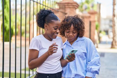 African american women mother and daughter using smartphone at street