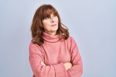 Middle age hispanic woman standing over isolated background looking to the side with arms crossed convinced and confident 