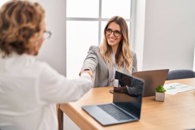 Man and woman business workers shake hands working at office