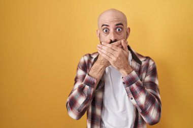 Sarı arka planda duran İspanyol sakallı adam ağzını yanlışlıkla elleriyle kapatarak şok etti. gizli kavram. 