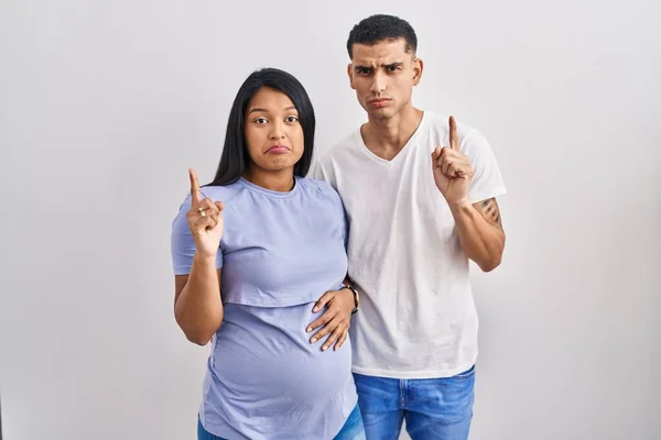 Jovem Casal Hispânico Esperando Bebê Sobre Fundo Apontando Para Cima — Fotografia de Stock