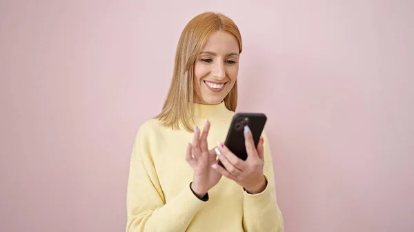 Молода Блондинка Посміхається Впевнено Використовуючи Смартфон Над Ізольованим Рожевим Тлом — стокове фото