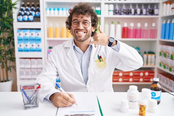 Hispanic Young Man Working Pharmacy Drugstore Smiling Doing Phone Gesture — Stock Photo, Image