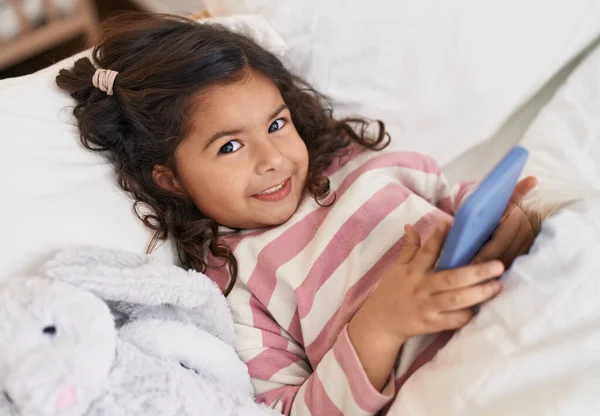 Adorable Hispanic Girl Using Smartphone Lying Bed Bedroom — Fotografia de Stock