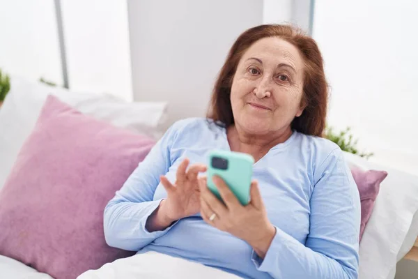 Senior Woman Using Smartphone Sitting Bed Bedroom — Zdjęcie stockowe