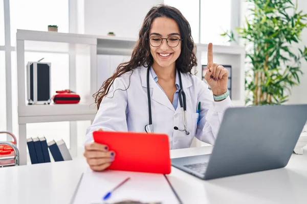 stock image Young doctor woman working on online appointment smiling with an idea or question pointing finger with happy face, number one 