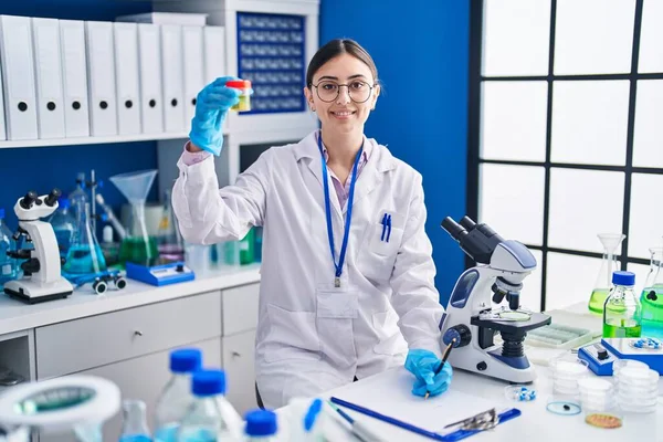 Young Hispanic Woman Scientist Writing Document Holding Urine Test Tube —  Fotos de Stock