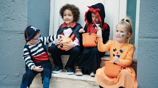 一群穿着万圣节服装的孩子在街上的南瓜篮里放糖果 — 图库照片