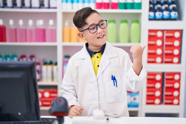 Jovem Hispânico Criança Trabalhando Farmácia Farmácia Apontando Polegar Até Lado — Fotografia de Stock