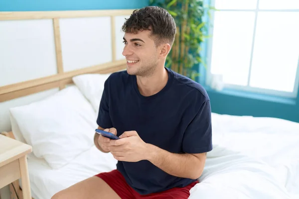 Young Hispanic Man Using Smartphone Sitting Bed Bedroom — Φωτογραφία Αρχείου