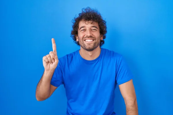 Mavi Arka Planda Duran Spanyol Genç Adam Bir Numarayı Gösterip — Stok fotoğraf