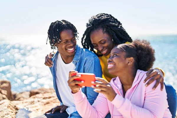 African American Friends Using Smartphone Sitting Rock Seaside — Fotografia de Stock