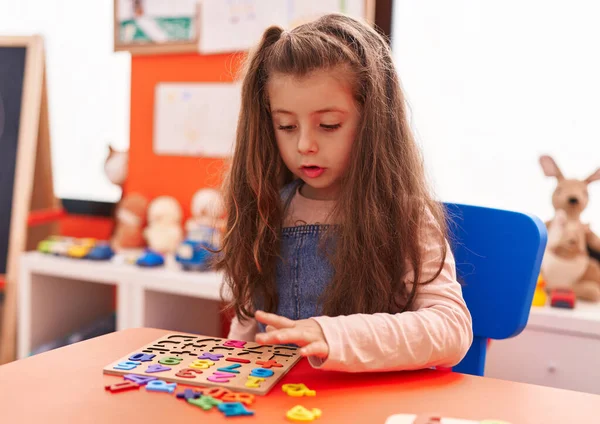 stock image Adorable hispanic girl playing with maths puzzle game sitting on table at kindergarten