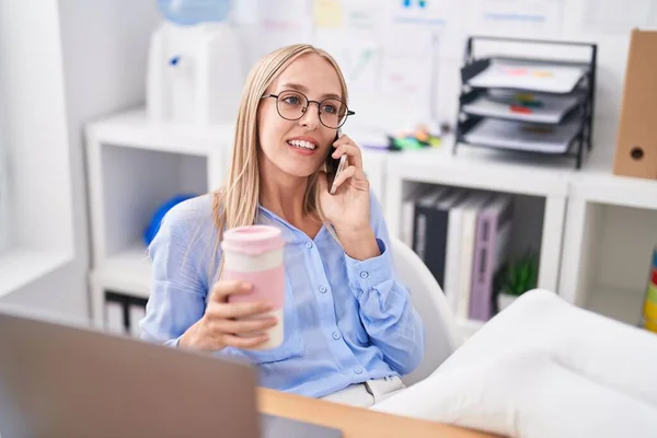 若いブロンド女性ビジネス労働者の話上のスマートフォン飲料コーヒーにオフィス — ストック写真