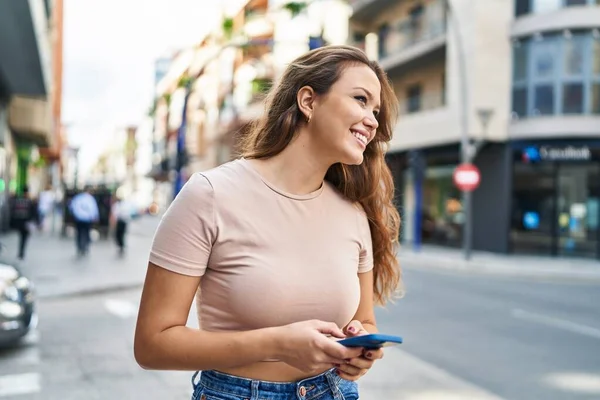 年轻美丽的惊慌失措的女人在街上用智能手机充满自信地微笑 — 图库照片