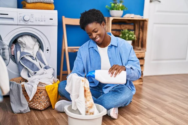 Mujer Afroamericana Sonriendo Confiada Vertiendo Detergente Camiseta Sucia Sala Lavandería —  Fotos de Stock