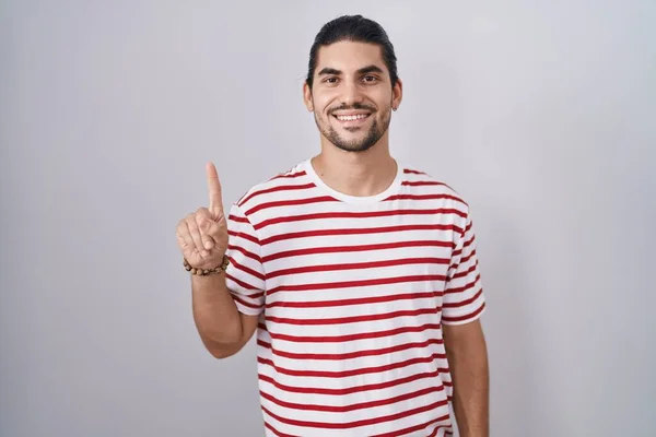 一个长头发的西班牙男人站在孤立的背景上 带着第一指尖 面带微笑 自信而快乐 — 图库照片