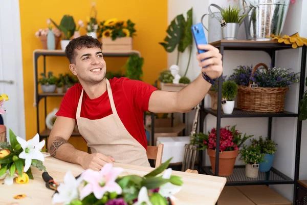 Young hispanic man florist make selfie by smartphone at flower shop