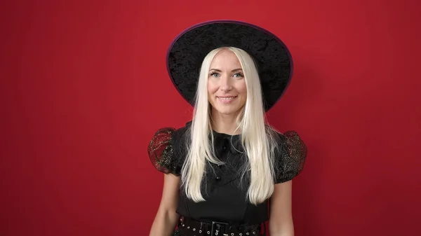 Junge Blonde Frau Hexenkostüm Lächelt Selbstbewusst Über Isolierten Roten Hintergrund — Stockfoto