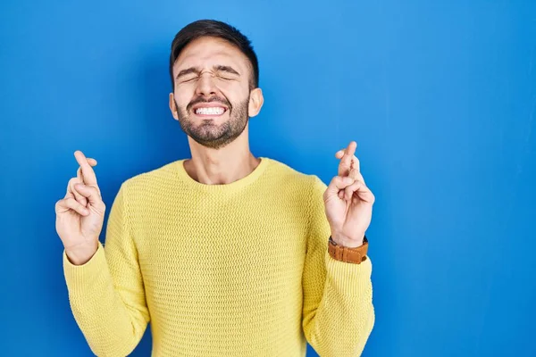 Homem Hispânico Sobre Fundo Azul Gesto Dedo Cruzado Sorrindo Com — Fotografia de Stock