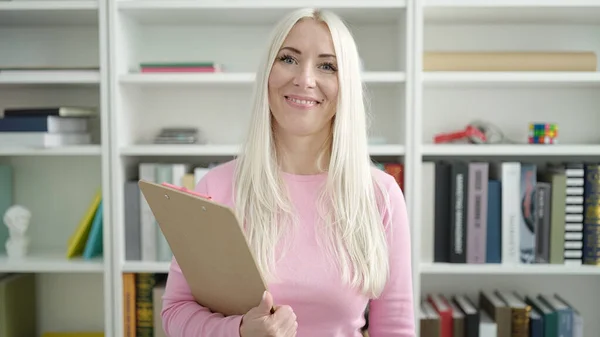 Jong Blond Vrouw Leraar Glimlachen Zelfverzekerd Holding Klembord Bibliotheek Universiteit — Stockfoto