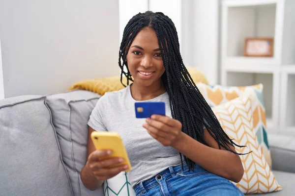 Afroamerykanka Pomocą Smartfona Karty Kredytowej Siedzi Kanapie Domu — Zdjęcie stockowe