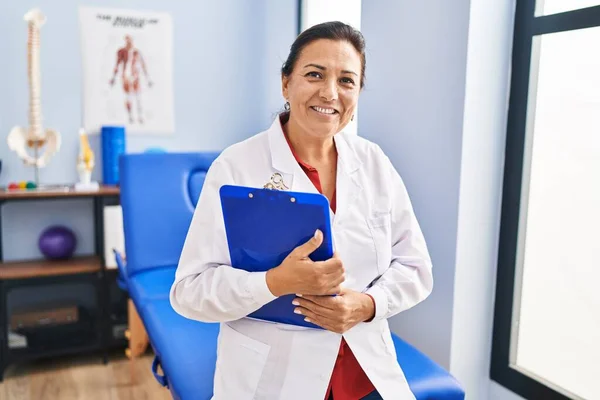 Middle Age Hispanic Woman Physiotherapist Holding Clipboard Rehab Clinic — Stockfoto