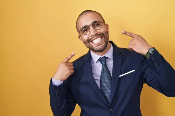 髭を生やしたヒスパニック系の男性がスーツを着て 笑顔を見せ 指の歯と口を指して結びます 歯の健康の概念 — ストック写真