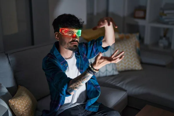 Young Hispanic Man Using Augmented Reality Glasses Sitting Sofa Home — Stockfoto