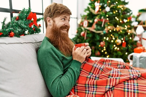 Mladý Ryšavý Muž Pije Kávu Sedí Vánočního Stromku Doma — Stock fotografie