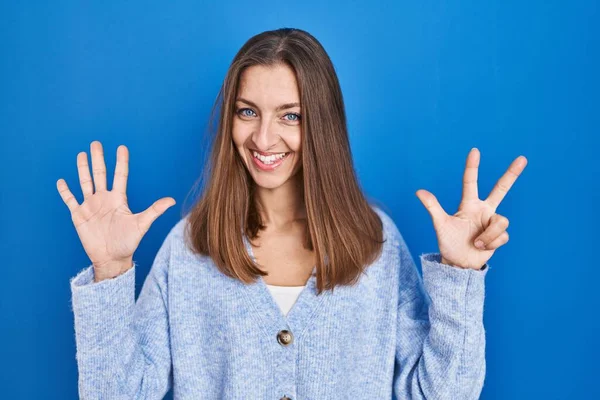 Młoda Kobieta Stoi Nad Niebieskim Tle Pokazując Wskazując Palcami Numer — Zdjęcie stockowe