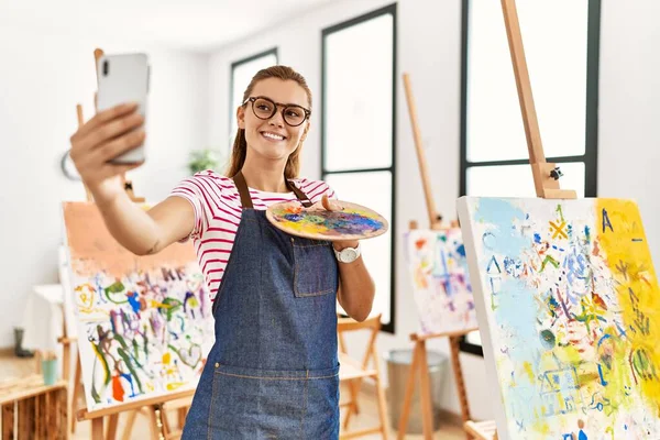 年轻女子面带微笑 自信地在艺术工作室的智能手机前自拍 — 图库照片