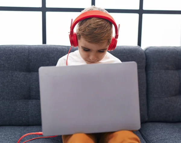 Evdeki Koltukta Oturan Dizüstü Bilgisayar Kulaklık Kullanan Sevimli Spanyol Çocuk — Stok fotoğraf