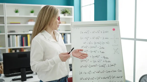 Young blonde woman teacher explaining maths exercise at library university